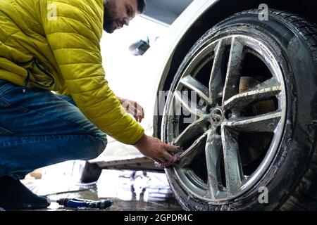 Nettoyage manuel des roues de voiture à l'aide d'éponges et de mousse. Banque D'Images