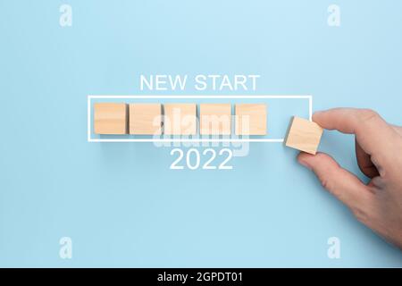 Nouveau concept START 2022. Chargement du nouvel an 2022 avec le cube en bois de mise à la main dans la barre en cours. Bonne année 2022. Démarrer le concept Banque D'Images