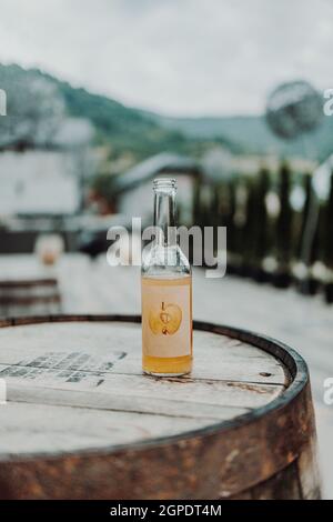 Bouteille en verre avec jus de pomme sur un vieux canon en bois en plein air Banque D'Images