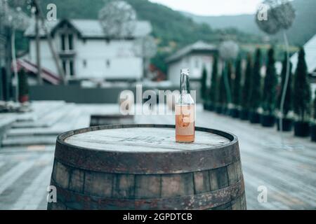 Bouteille en verre avec jus de pomme sur un vieux canon en bois à l'extérieur dans le café de rue.Aliments biologiques sains. Banque D'Images