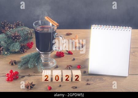 maquette d'ordinateur portable et vin chaud sur table pendant le nouvel an 2022. Bonne année 2022. Lettrage créatif bonne année 2022. Liste de tâches et plans pour 2 Banque D'Images