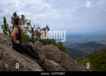 une jeune femme athlétique au sommet de la montagne regarde au loin Banque D'Images