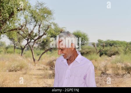 Portrait en gros plan d'un agriculteur d'origine indienne, homme âgé souriant à l'extérieur de la forêt et portant une chemise blanche Banque D'Images