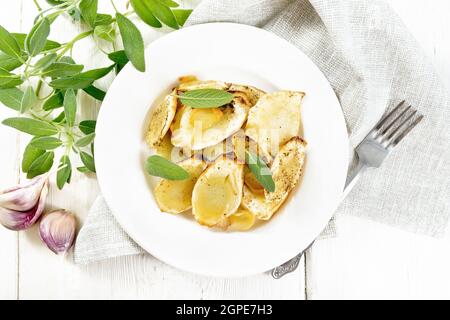 Panais cuits aux épices, à l'ail et à la sauge dans une assiette sur une serviette en bois sur fond de tableau de dessus Banque D'Images