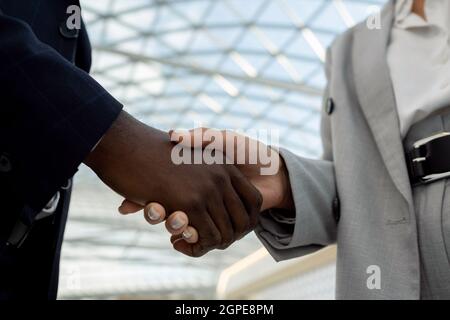 Mains de partenaires multiraciaux pendant la poignée de main après la négociation et la signature du contrat Banque D'Images