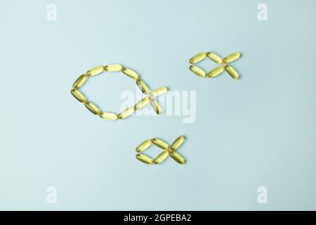 Les capsules oméga 3 d'huile de poisson sont disposées en forme de poisson sur fond bleu Banque D'Images