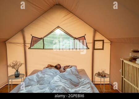 Couple paisible dormant paisiblement sur un lit double dans la chambre de la maison de glamping Banque D'Images