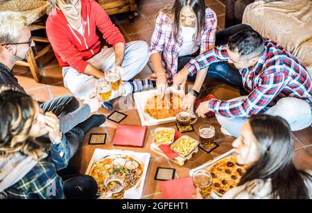 Des amis heureux mangeant de la pizza à emporter à la maison après le travail - concept d'amitié avec les jeunes qui profitent du temps ensemble et s'amuser vraiment Banque D'Images