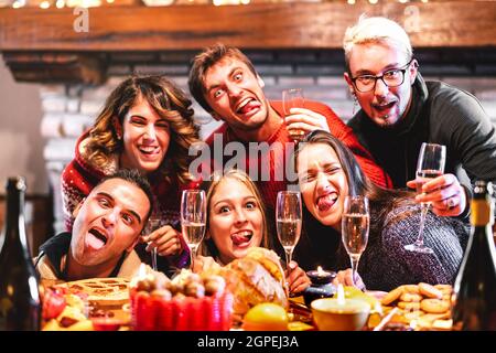 Des amis heureux prenant un selfie fou en train de célébrer Noël avec du champagne et des bonbons à la nourriture au dîner de réunion - concept de vacances d'hiver Banque D'Images