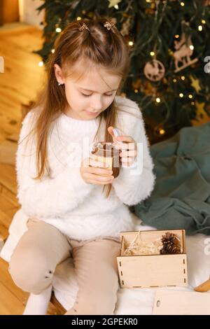 Une jeune fille mange du beurre d'arachide sur fond de Noël Banque D'Images