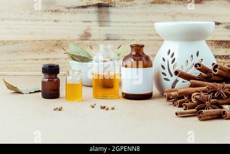 Bouteille d'huile essentielle pour le massage ayurvédique avec le bâton de cannelle, l'anis étoilé et les feuilles de laurier avec focus sélectif sur fond de bois minable . Banque D'Images