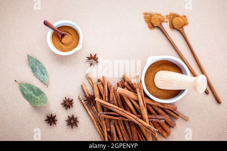 Composition de bâton de cannelle et la cannelle en poudre dans un mortier blanc à la badiane, les feuilles de laurier et cuillère en bois sur fond brun . Banque D'Images