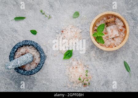 Sel rose de l'Himalaya dans le bol en bois avec la menthe poivrée ,sage,le thym, le basilic et l'origan sur fond de pierre. Sel de l'himalaya utilisé pour la cuisson et pour Banque D'Images