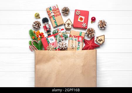 Boîtes cadeau rouges et vertes enveloppées à la main, ornées de rubans, flocons de neige et chiffres, décorations de Noël et décoration en sac sur table blanche Noël Banque D'Images