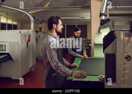 Les travailleurs de l'usine de chaussures travaillant avec une machine à découper dans un atelier de fabrication de chaussures Banque D'Images