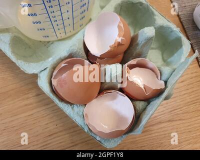 Quatre coquilles d'œufs cassées dans un emballage en carton d'œufs ayant été utilisées comme ingrédient de cuisson et prêtes à être recyclées comme déchets alimentaires Banque D'Images