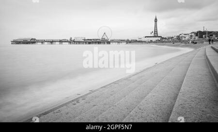 Blackpool Tower et Central Pier en monochrome vu le long des marches incurvées qui occupent le bord de la plage pour protéger la ville de l'Irish S. Banque D'Images