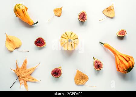 Arrière-plan d'automne avec citrouilles, figues découpées en moitié et feuilles d'automne sur fond blanc. Fruits frais et gourdes jaunes. Concept d'automne. Vue de dessus, fl Banque D'Images