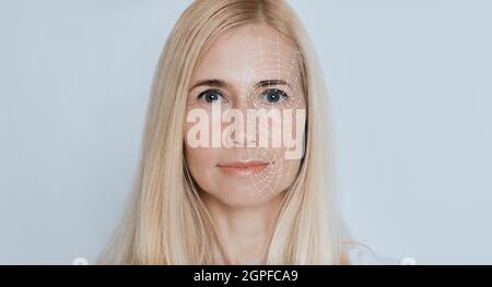 Une dame blonde se fait scanner le visage sur fond de studio, gros plan, collage Banque D'Images