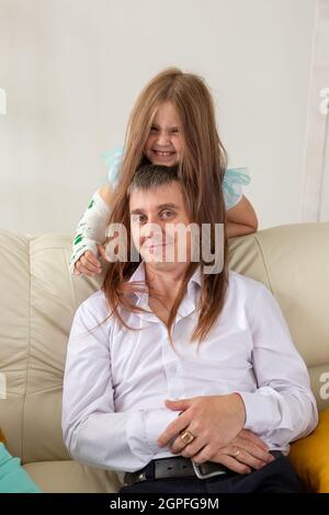 Père et sa fille s'amusent dans leur salon. Petite fille ont la main blessée mais elle est heureuse être ensemble son père Banque D'Images