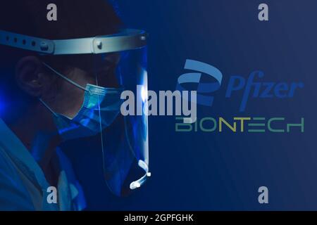 Sarajevo, Bosnie-Herzégovine - 09.09.2021: Docteur avec écran facial et masque pour covid-19 avec le logo Pfizer et Biontech en arrière-plan Banque D'Images