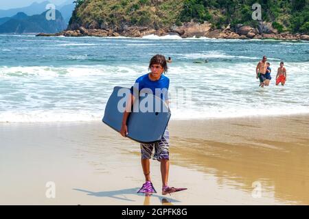 Jeune brésilien avec planche à voile sur la plage de Piratininga à Niteroi, Rio de Janeiro, Brésil. La plage est un endroit célèbre et une trave Banque D'Images