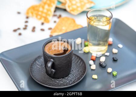 Café turc traditionnel dans une tasse moderne noire avec de l'eau et du sucre. Mise au point sélective Banque D'Images