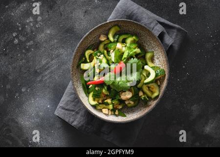 Salade asiatique épicée de concombre avec coriandre fraîche, gingembre, piment, vinaigre noir sur fond noir. Concombres épicés. Populaire chinois appe Banque D'Images
