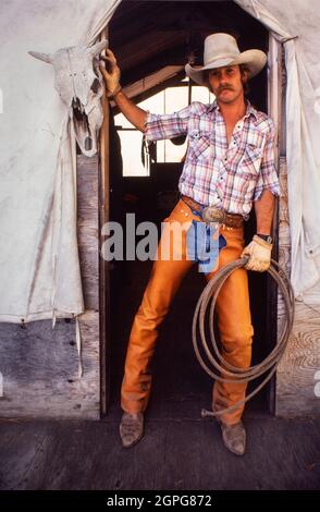 Cowboy assis devant un panneau de pause coeur sur la tente dans le Wyoming USA Banque D'Images