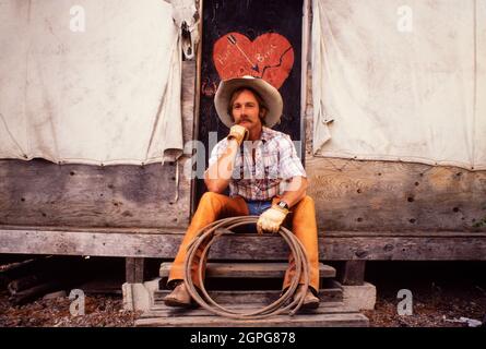 Cowboy assis devant un panneau de pause coeur sur la tente dans le Wyoming USA Banque D'Images