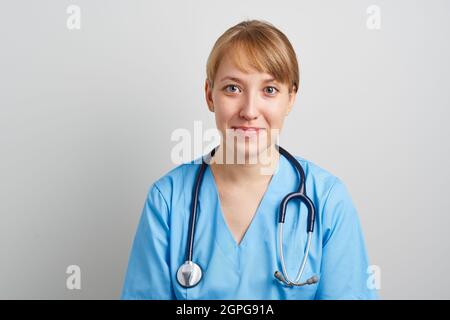 Jeune infirmière travailleuse de soins de santé avec stéthoscope en uniforme bleu regardant la caméra Banque D'Images