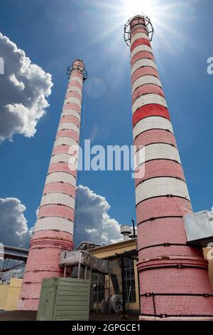 Cheminées d'usines industrielles. Extérieur de l'installation de chauffage urbain avec cheminées industrielles contre le soleil et le ciel bleu. Vue à angle bas. Banque D'Images