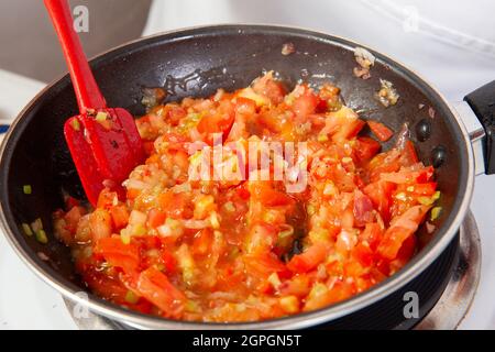 Préparation de la sauce traditionnelle colombienne hogao ou criollo (salsa criolla) à base d'oignons, de tomates, de poivrons et de coriandre Banque D'Images