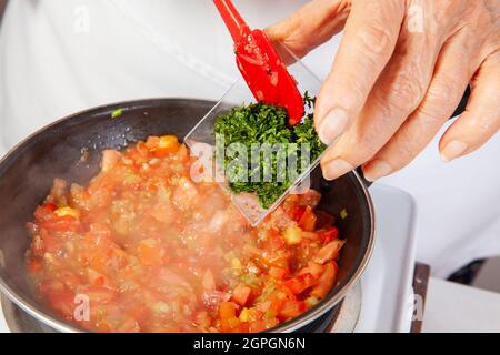 Préparation de la sauce traditionnelle colombienne hogao ou criollo (salsa criolla) à base d'oignons, de tomates, de poivrons et de coriandre Banque D'Images