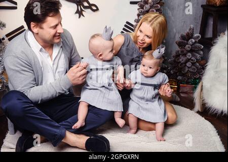 Une grande famille heureuse avec des enfants jumeaux dans l'intérieur de la maison du nouvel an sur fond d'une grande horloge. Banque D'Images