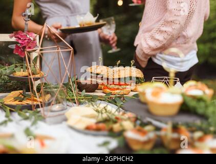 Des femmes anonymes tenant des assiettes et drinksat partie de jardin informelle. Naturel. Image de style de vie. Banque D'Images