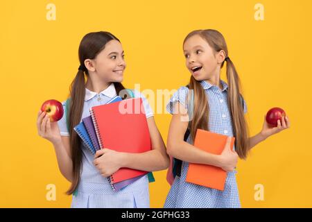 Refaites le bon début de l'école. Les enfants heureux tiennent des livres et des pommes. Une alimentation saine. Nutrition scolaire Banque D'Images