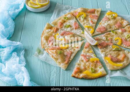 Tarte flambé au saumon, au poivre jaune et aux ciboules sur fond bleu clair Banque D'Images