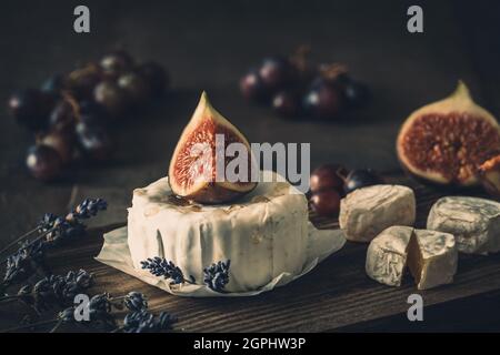 Fromage doux rond entier avec figue et miel sur bois rustique sombre Banque D'Images