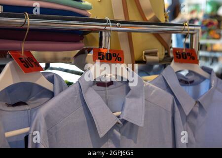 Rabais étiquettes de solde 50 % de rabais sur les cintres avec vêtements dans une boutique de vêtements décontractés ou à la maison. Mode concept, saison de réduction, vendredi noir, shopping hors ligne Banque D'Images