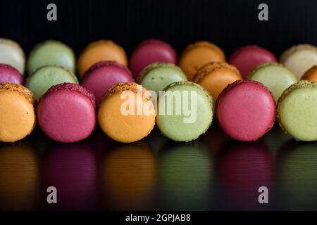 Macaron ou macarons français un cookie de dessert fait de meringue et d'amande reflété sur une table noire Banque D'Images