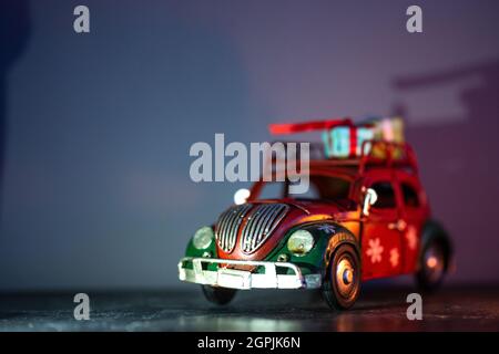 Figurines décoratives sur le thème de Noël. Une statuette d'une voiture rouge avec des cadeaux sur le toit. Banque D'Images