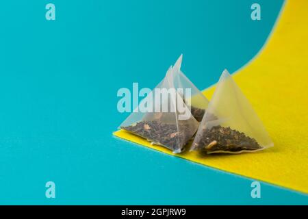 thé vert dans un sac de pyramide sur fond jaune bleu. Banque D'Images