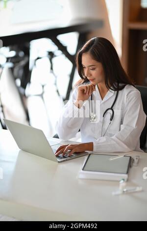 Portrait d'une jeune femme asiatique médecin utilisant un ordinateur portable pour mener une conférence en ligne avec un patient. Consultation médicale avec une équipe de s. Banque D'Images