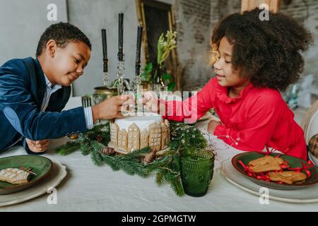 Soeur et frère décorant gâteau de pain d'épice à la maison. Concept de loisirs en famille pour Noël. Idée pour les friandises faites à la main Happy Year de bricolage. Banque D'Images