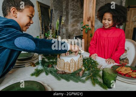 Soeur et frère décorant gâteau de pain d'épice à la maison. Concept de loisirs en famille pour Noël. Idée pour les friandises faites à la main Happy Year de bricolage. Banque D'Images