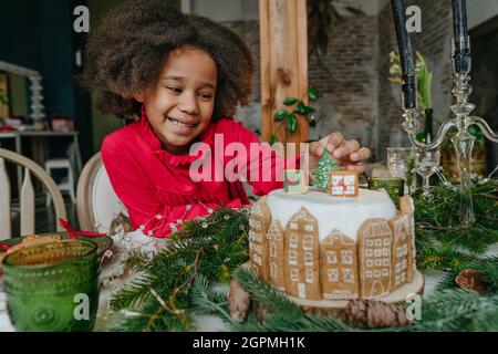 Fille décorant gâteau de pain d'épice à la maison. Concept de loisirs en famille pour Noël. Idée pour les friandises faites à la main Happy Year de bricolage. Mise au point sélective sur le g Banque D'Images