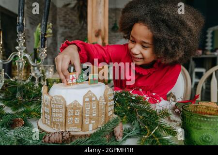 Fille décorant gâteau de pain d'épice à la maison. Concept de loisirs en famille pour Noël. Idée pour les friandises faites à la main Happy Year de bricolage. Mise au point sélective. Banque D'Images