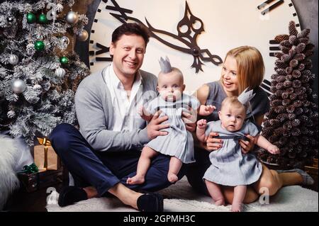 Une grande famille heureuse avec des enfants jumeaux dans l'intérieur de la maison du nouvel an sur fond d'une grande horloge. Banque D'Images