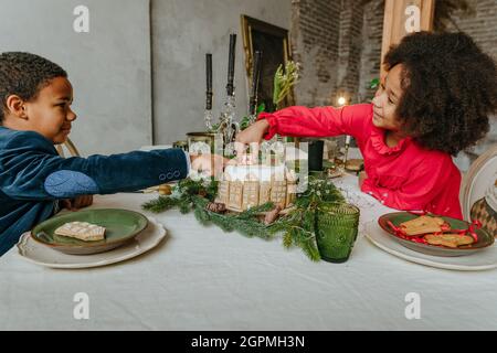 Soeur et frère décorant gâteau de pain d'épice à la maison. Concept de loisirs en famille pour Noël. Idée pour les friandises faites à la main Happy Year de bricolage. Banque D'Images